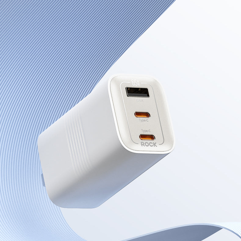 A 65W GAN Wall Charger with three colored ports for different types of connections, placed on a light blue surface.